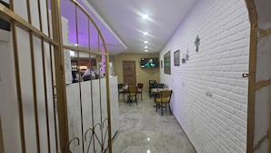A hallway with a white brick wall, a TV mounted on the wall, and a door with a wooden frame.