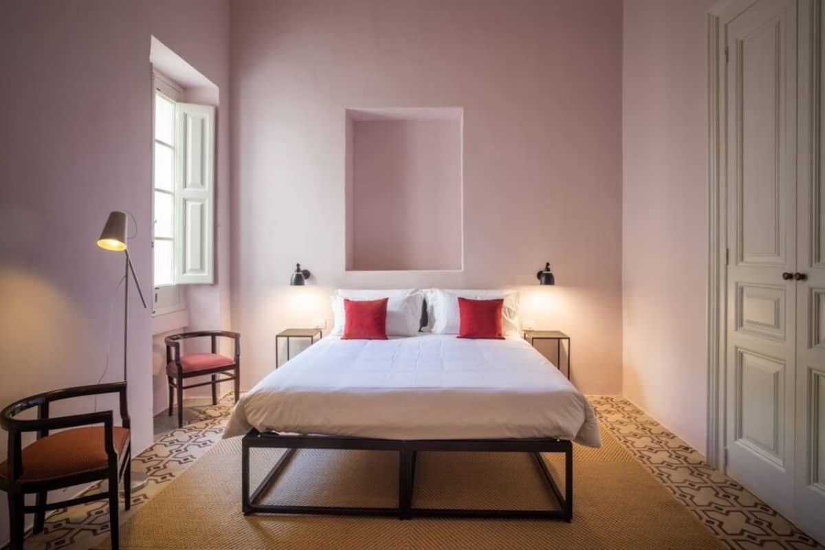 Une chambre à coucher avec un lit, deux chaises, une lampe et un sol à motifs.