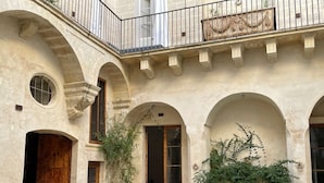 A courtyard with arched doorways, a wooden door, and potted plants. - PALAZZO GARZIA - Dimora Storica (Maglie)