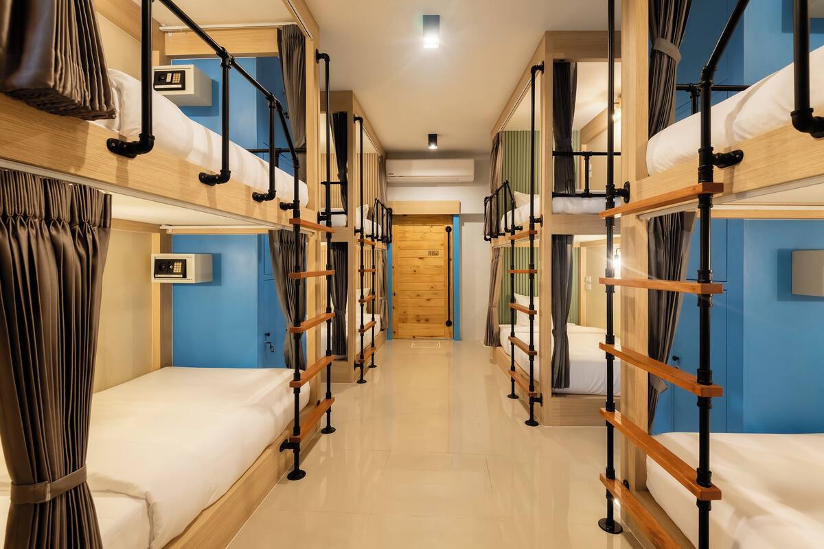 A hotel room with bunk beds, a wooden door, and a blue wall.