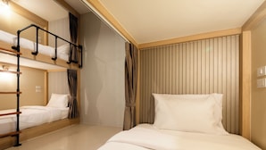 A hotel room with bunk beds, a wooden headboard, and a large window with curtains.