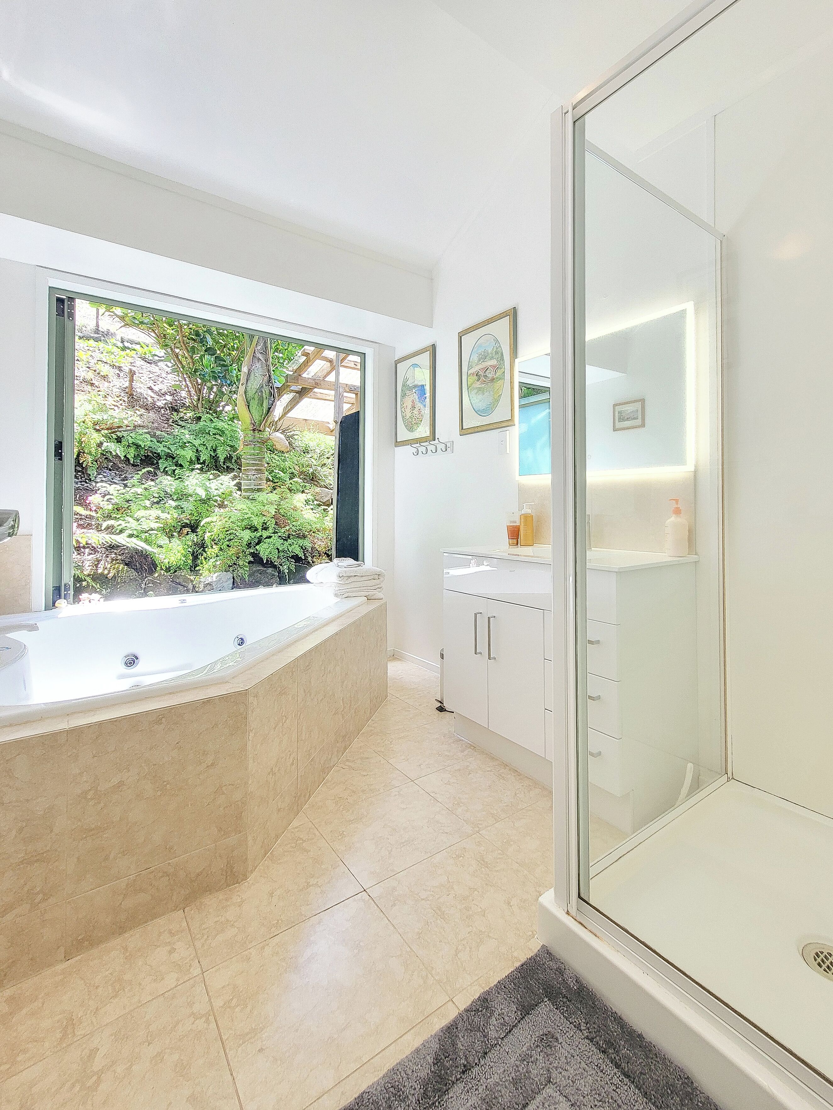 Une salle de bain moderne avec une baignoire sur pieds, une douche à parois de verre et un lavabo avec un miroir.