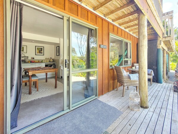 Un edificio de madera con puerta corrediza de vidrio que da a un comedor con mesa y sillas.
