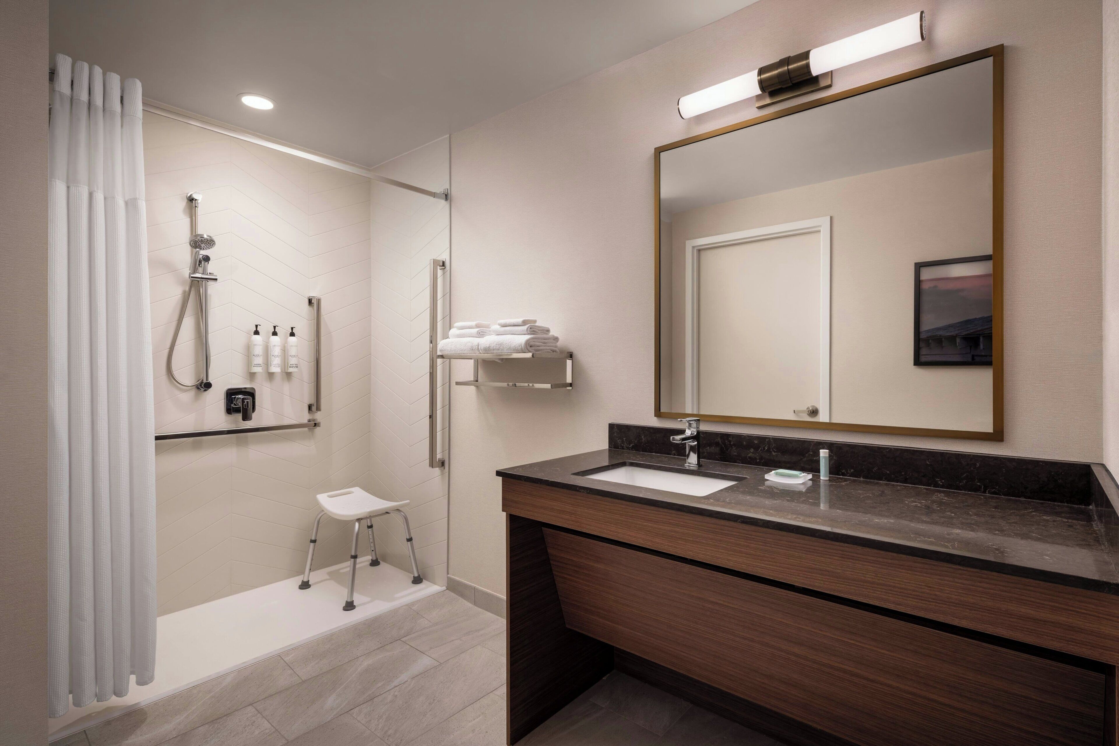 A modern bathroom with a shower, a sink, a vanity, and a large mirror.