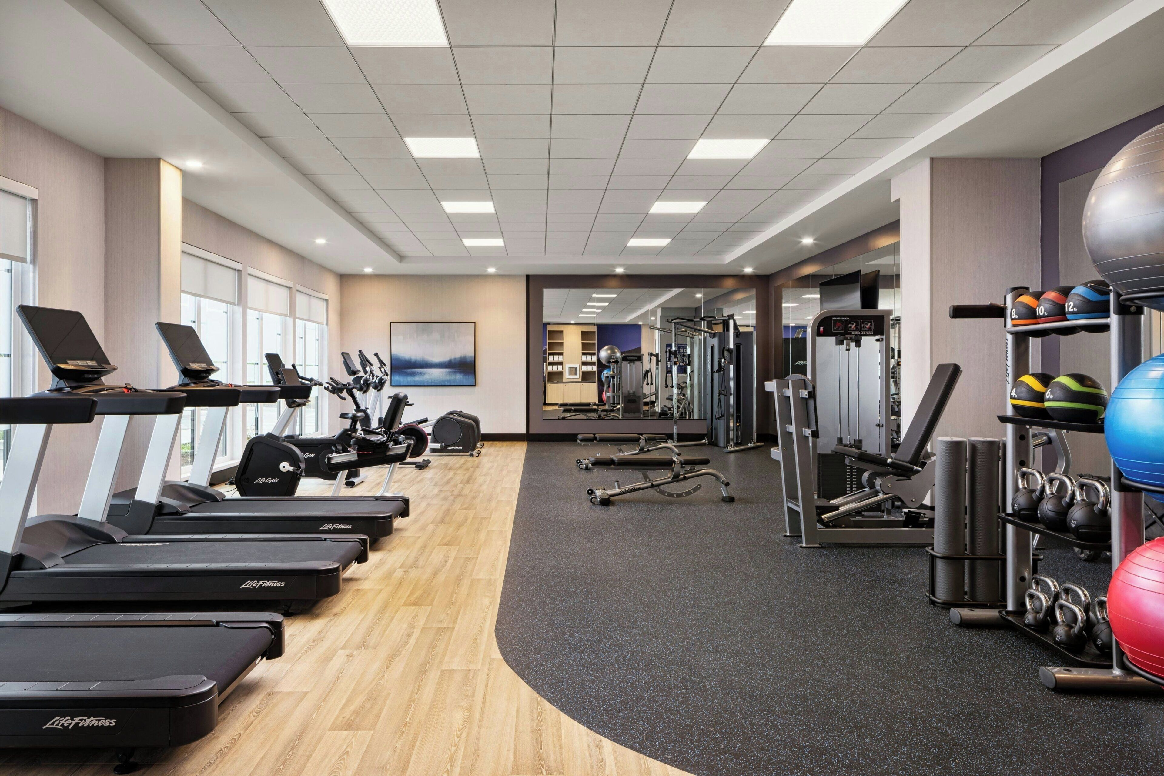 A gym with treadmills, weight machines, and exercise balls.