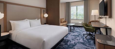 Une chambre d’hôtel avec un grand lit, un bureau, une chaise, une télévision et une fenêtre avec des rideaux.