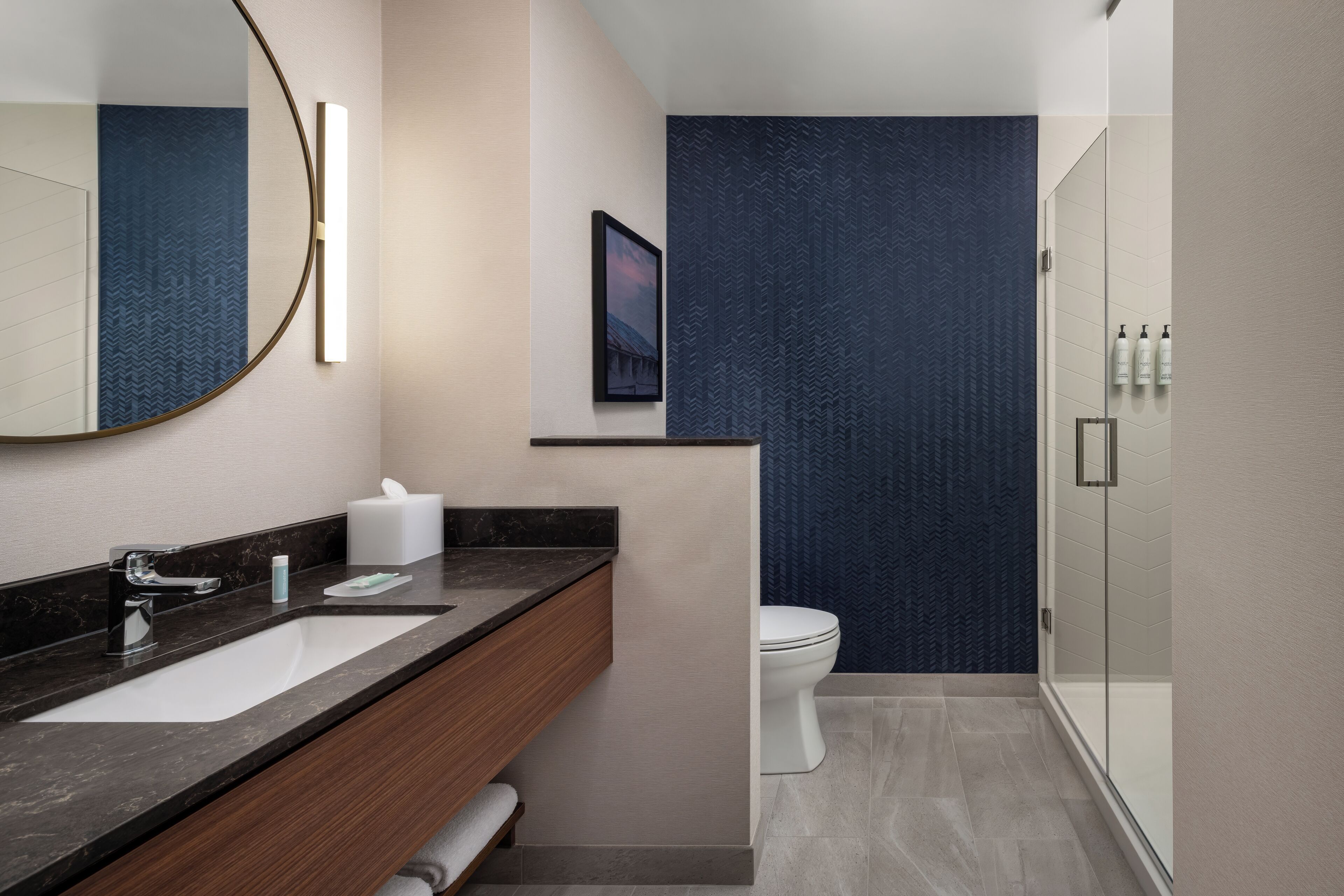 A modern bathroom with a large mirror, a sink, a toilet, and a shower area.