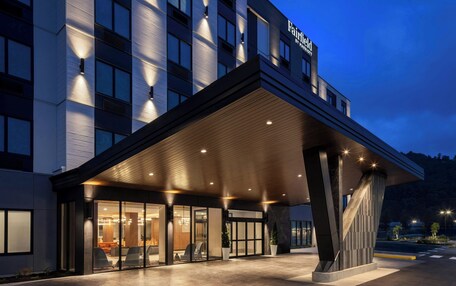 A modern hotel entrance with a covered outdoor area and a visible restaurant inside.