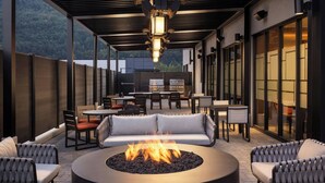 An outdoor patio with a round fire pit, seating, and a grill area. - Fairfield by Marriott Inn & Suites Chilliwack (CHILLIWACK)