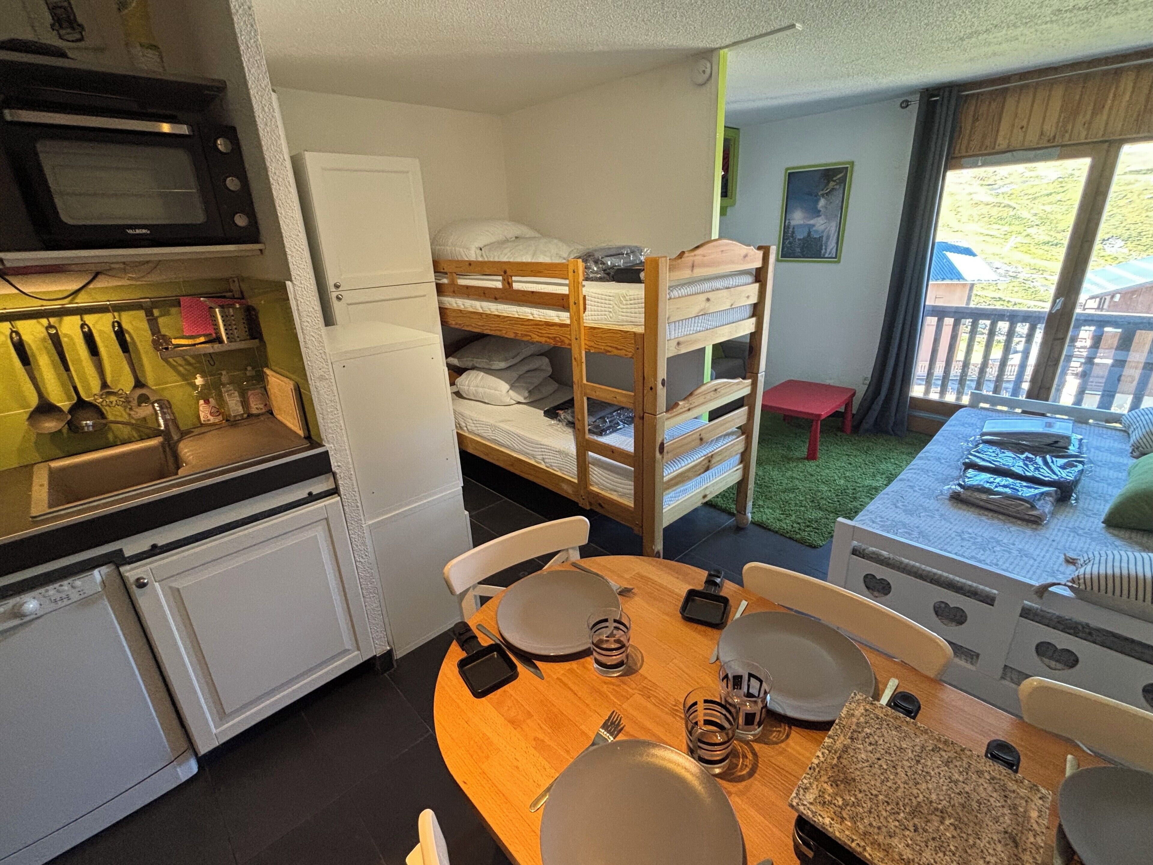 A compact kitchen with a microwave, sink, and a dining area with a table set for two.