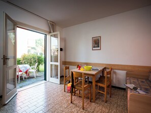 A room with a wooden table and chairs, a bed, and a door leading to a balcony. - Townhouse with garden and pool in Bibione (Bibione)