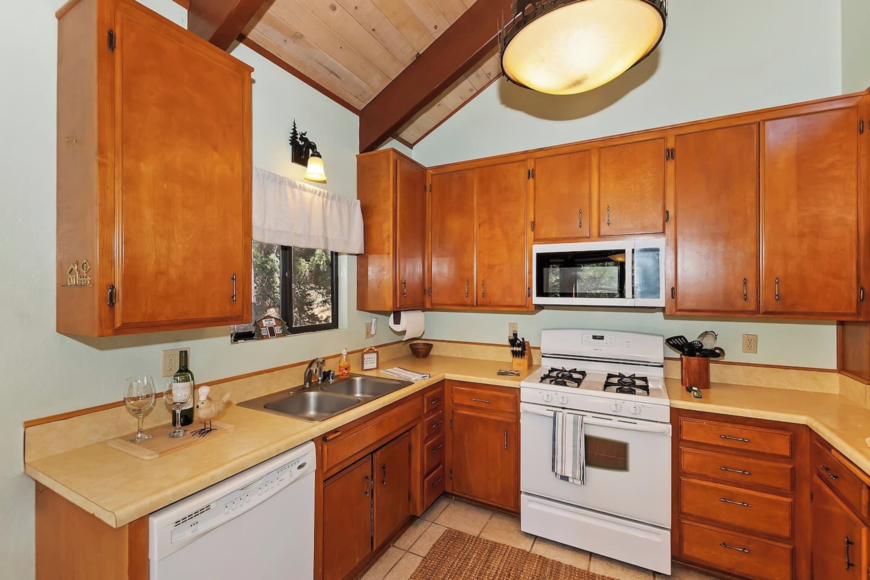 Une cuisine avec des meubles de rangement en bois, un lave-vaisselle, une cuisinière et un four à micro-ondes.