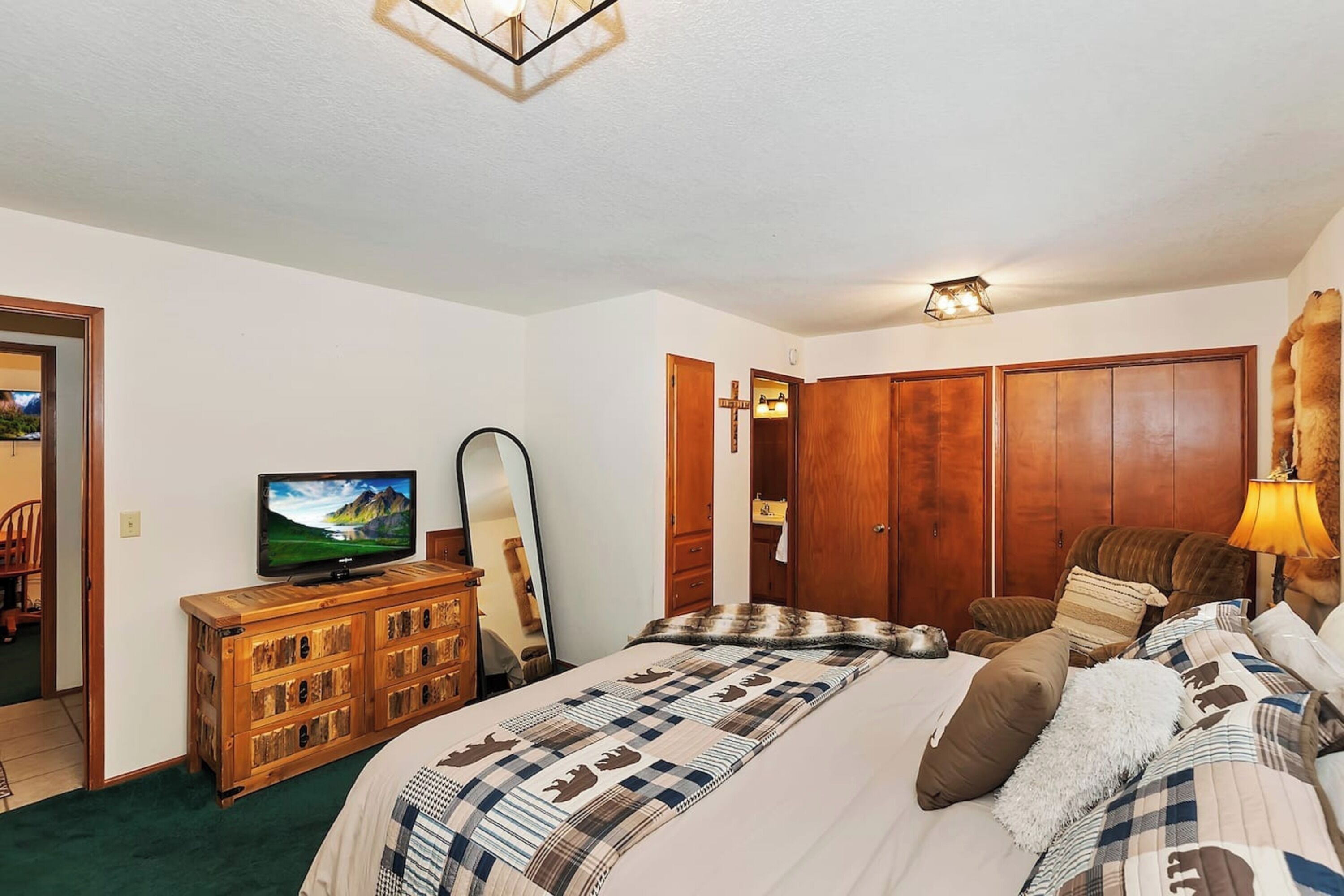 Une chambre à coucher avec un lit, une armoire en bois, une télévision et un miroir.