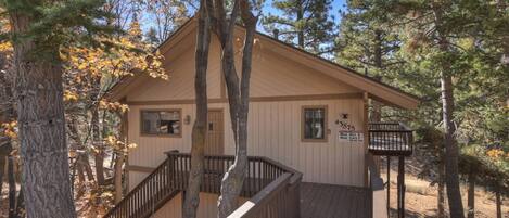A cabin with a wooden deck, a staircase, and a sign indicating a maximum occupancy of 6 people.