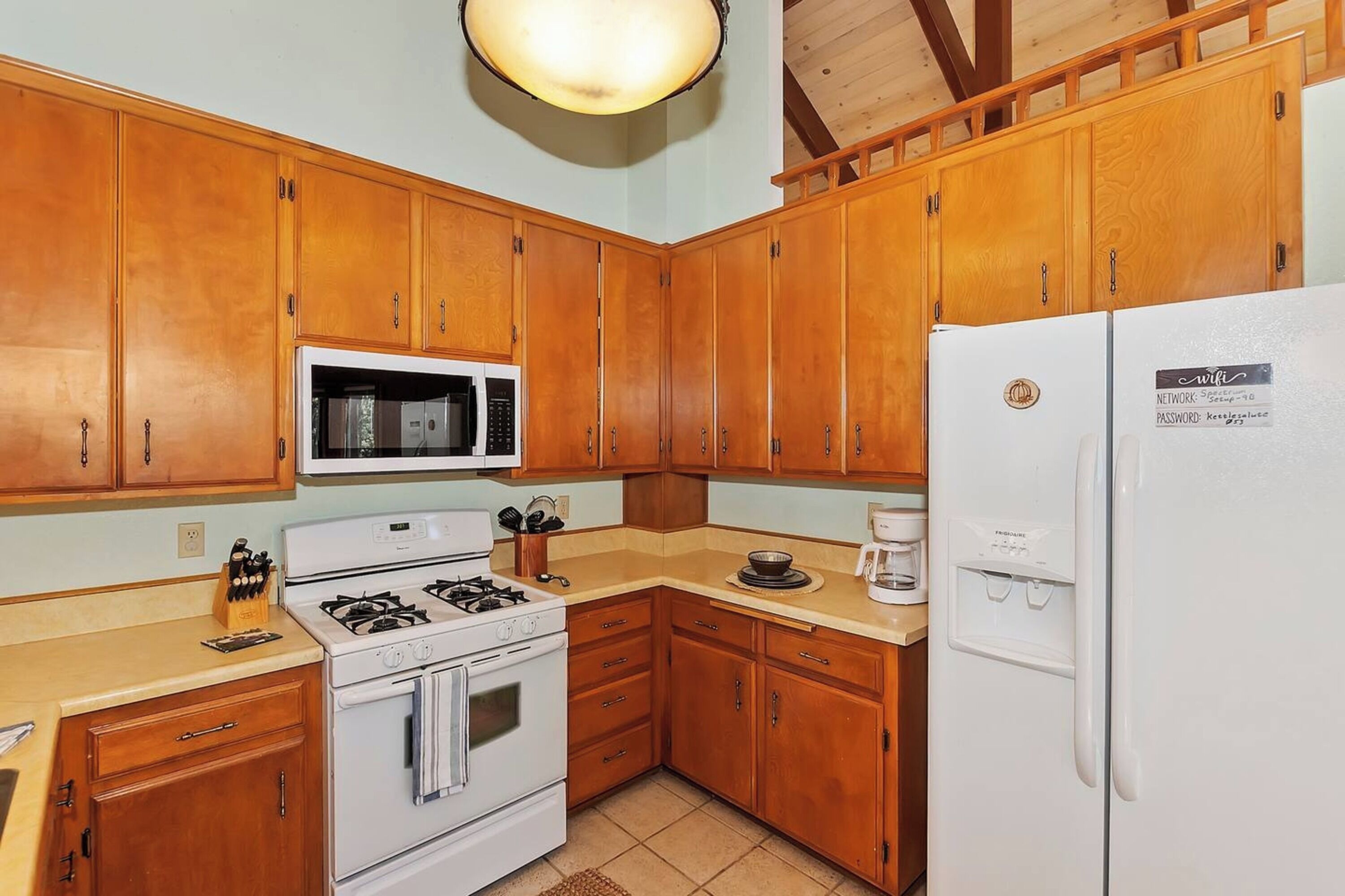 Une cuisine avec des meubles de rangement en bois, un four blanc, un four à micro-ondes et un réfrigérateur.