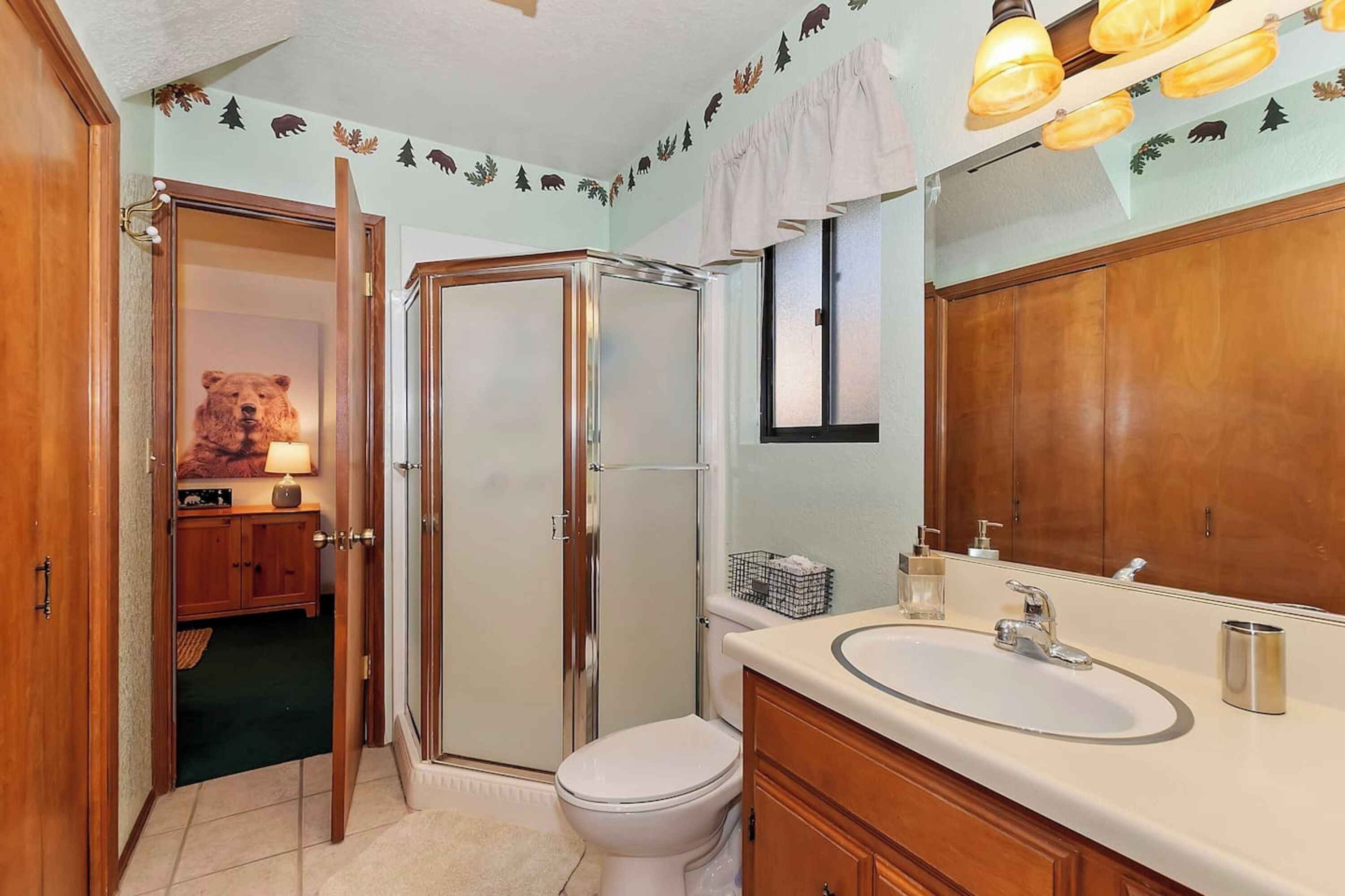A bathroom with a wooden vanity, a toilet, and a glass shower enclosure.