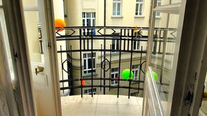 A balcony with a metal railing, a view of adjacent buildings, and a tiled floor. - Central Station Hostel (Warsaw)