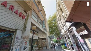 Une rue étroite bordée de boutiques, dont une dont la devanture, bien visible, porte une enseigne indiquant « CARUSEL ».