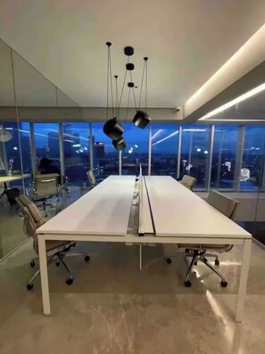 A modern conference room with a long table, chairs, and pendant lighting.