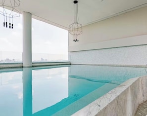 A modern indoor swimming pool with a clear view of the city skyline.