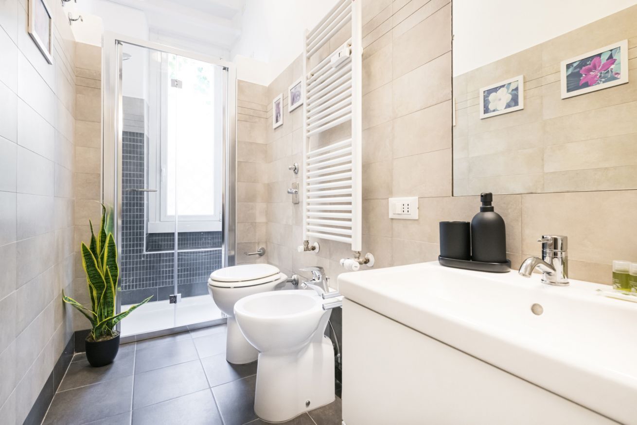 Une salle de bain moderne équipée d’une douche, de toilettes, d’un bidet et d’un grand lavabo.