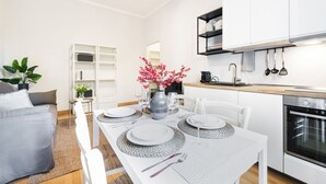 Una cocina moderna con armarios blancos, horno empotrado y estante negro sobre el fregadero.