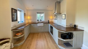 A kitchen with a central island, a window, and a built-in oven. - Charming countryside retreat (Cross in Hand)