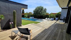 A wooden deck with a pool, a cactus, and a chair. - L'Ecrin contemporain (Nages-et-Solorgues)