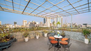 A rooftop terrace with a glass ceiling, potted plants, and outdoor seating. - Ben's House Boutique (Da Nang)