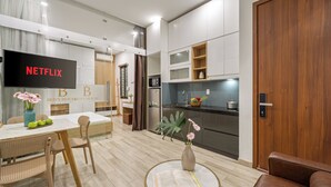 A modern living room with a dining area, a kitchen, and a TV displaying 'NETFLIX'. - Ben's House Boutique (Da Nang)