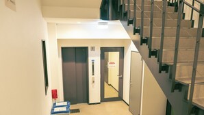 A hallway with a staircase, a door marked with the number 1, and a fire extinguisher. - Hotel SaintFelician Kyoto Shijo Karasuma (Kyoto)