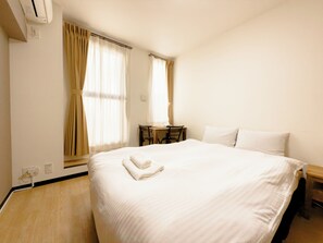 Una habitación de hotel con una cama grande, un escritorio y una silla.