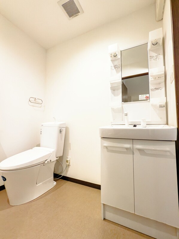 A small, clean bathroom with a toilet, sink, and mirror.