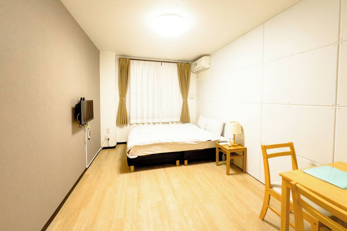 Une chambre d’hôtel comprenant un lit, une table de chevet, une chaise et une petite table avec une lampe.