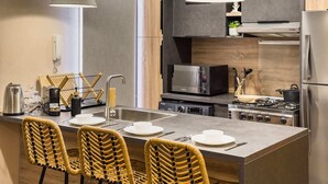A modern kitchen with a central island, stainless steel appliances, and wicker chairs. - Xuru Stays I The 1bdr Rustic Rooftop w/ Wow Outdoor Terrace (Cairo)