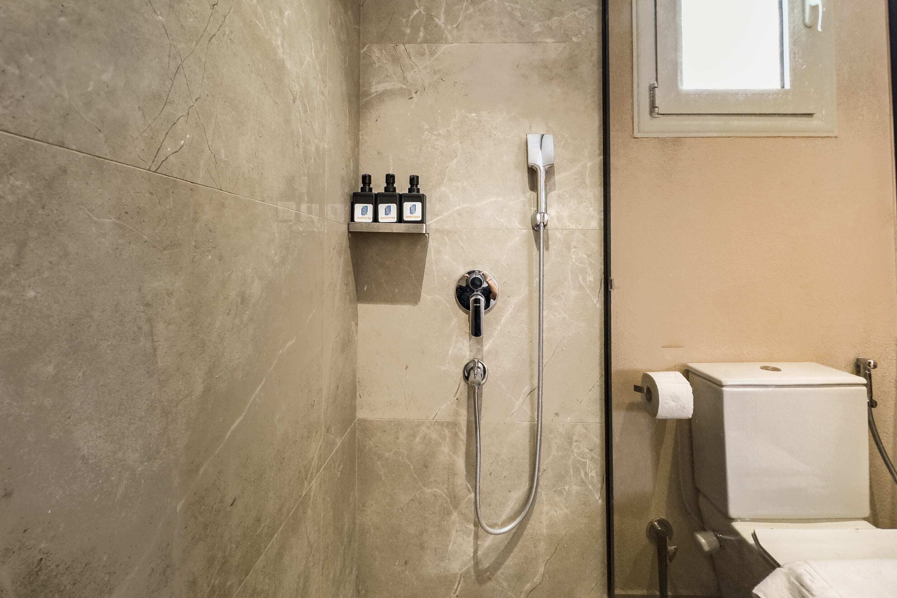 Een badkamer met een douche, toilet en een plank met toiletartikelen.