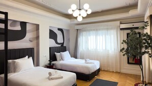 A hotel room with two beds, a modern chandelier, a large abstract painting, a potted plant, and a view of the outdoors through sheer curtains. - Xuru Stays I The 2bdr Crimson Crib @ The Heart Of Heliopolis (Cairo)