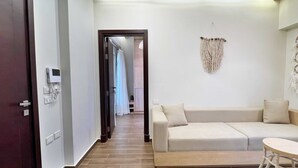 A modern living room with a sofa, a small round table, and a macrame wall hanging. - Xuru Stays I New Cairo Studios (New Cairo)