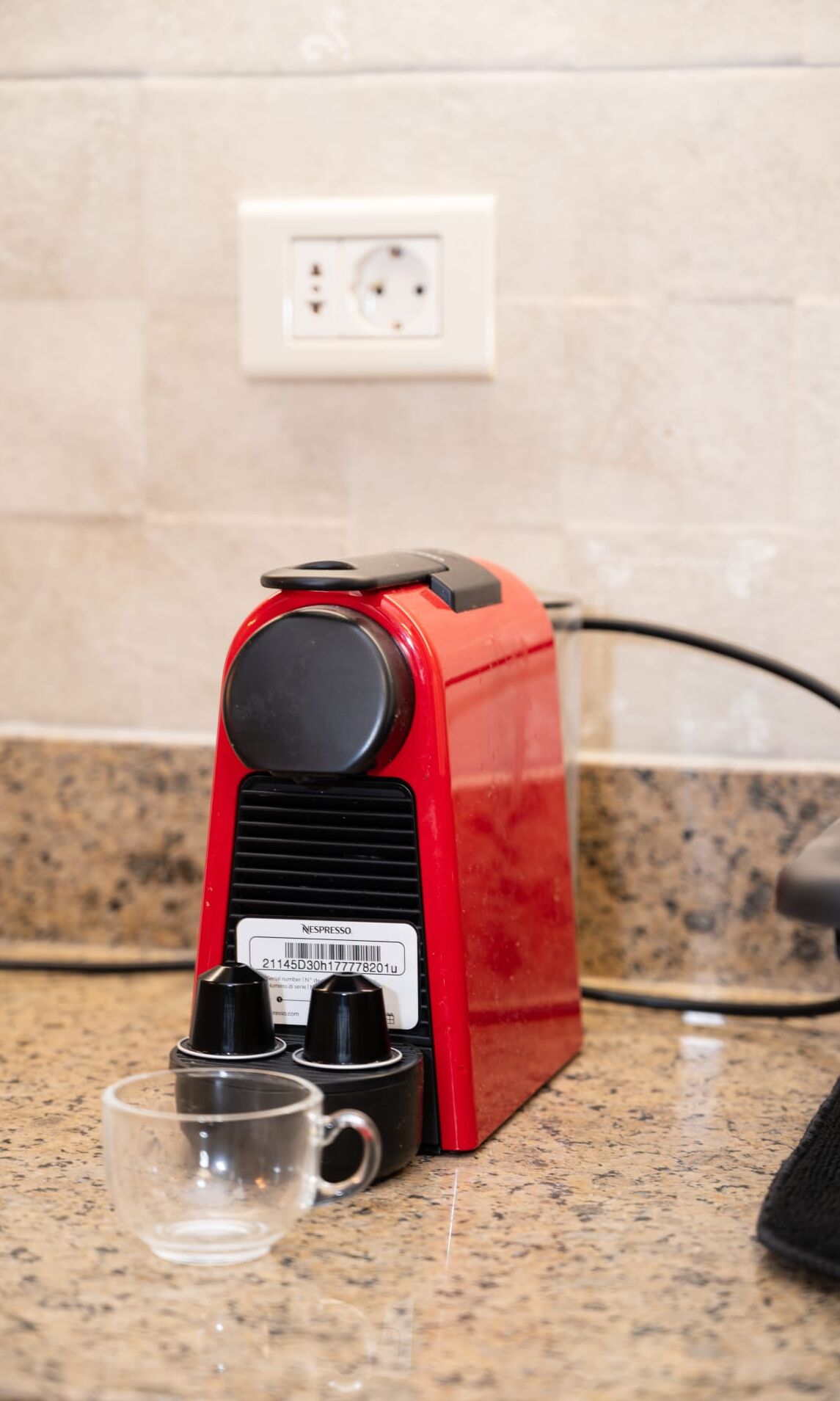 Una máquina de café espresso roja con una etiqueta de código de barras sobre una encimera de cocina.