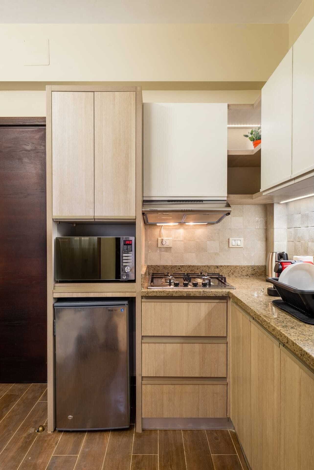 Una cocina compacta con microondas integrado, un refrigerador de acero inoxidable y una estufa a gas.
