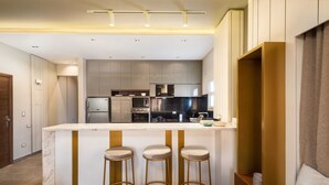 A modern kitchen with a central island, bar stools, and built-in appliances. - Xuru Stays I The Sleek & Ritzy 2 BDR 15 min From CAI Airpt (New Cairo)