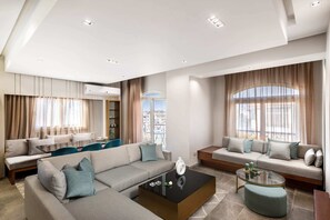 A modern living room with a sectional sofa, a glass coffee table, and a view of the city through large windows. - Xuru Stays I The Sleek & Ritzy 2 BDR 15 min From CAI Airpt (New Cairo)