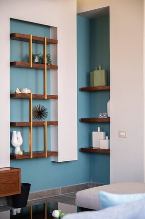 A modern bathroom with a blue wall, wooden shelves, and a grey bathtub. - Xuru Stays I The Sleek & Ritzy 2 BDR 15 min From CAI Airpt (New Cairo)