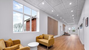 Een ruim, modern interieur met een houten vloer, grote ramen en een zithoek met een bank en een bijzettafeltje.