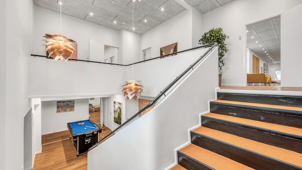 Een modern interieur met een trap, houten vloeren en een pooltafel.