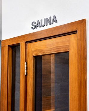 Une porte en bois, au-dessus de laquelle est affiché un panneau indiquant « SAUNA ».