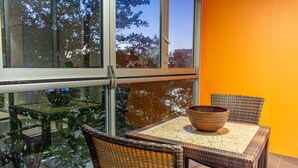 Une table en verre, des chaises en osier et un saladier, le tout placé devant un mur d’un orange vif.
