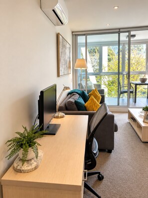 Un espace de bureau moderne comprenant un bureau, un ordinateur et un coin salon confortable avec un canapé et des coussins.