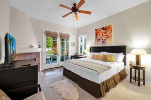 A bedroom with a bed, a ceiling fan, a TV, a lamp, and a painting on the wall.
