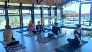 A group of people sitting on yoga mats in a spacious room with large windows and a view of the outdoors. - DaLart Glamping & Coffee (Duc Trong)